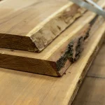 Thickness of an unedged acacia board on a wooden panel close-up.