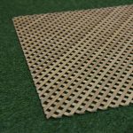 Full oak lattice grille panel laid diagonally across artificial turf, showing its diamond pattern.