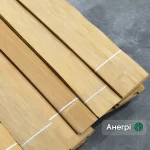 Bundles of 0.6 mm sliced anegre veneer sheets bound together on a grey floor