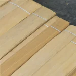 Bundles of light beige 0.6 mm sliced anegre veneer sheets tied with white straps.