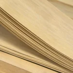 Close-up of a pack of 0.6 mm sliced Anegre veneer sheets showing natural wood grain.