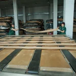 Warehouse workers lay long sheets of 0.6 mm sliced Anegre veneer on a measurement table.