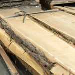 Unedged acacia lumber boards stored in a stack at the warehouse