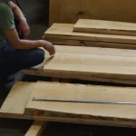 A worker inspects dry unedged acacia boards of grade 1 in the warehouse.