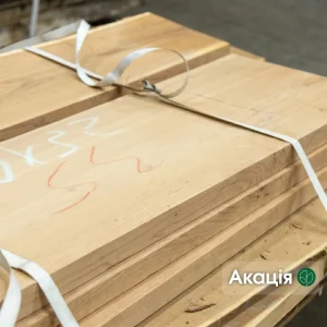 Stack of first grade dry edged acacia boards bound with straps in warehouse