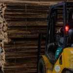Kiln-dried 52 mm unedged elm boards being loaded by a forklift in the warehouse.