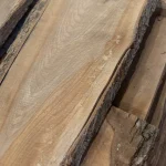 Wood grain texture of an unedged 52 mm elm board with natural bark edges visible close up.