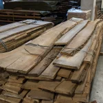 Stack of grade 1, 52 mm unedged elm boards bound together in a warehouse setting.