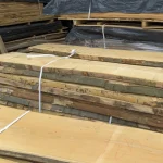 Unedged 52 mm beech boards tied in a stack at a lumber warehouse.