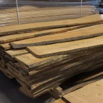 Warehouse stack of kiln-dried unedged cherry wood boards ready for sale.