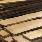 Various widths and natural waney edges of stacked cherry lumber boards.