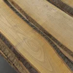 Wood grain texture and natural waney edge of extra grade unedged cherry boards.