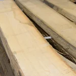 Top-down view of stacked unedged red oak boards showing their thickness and natural waney edges.