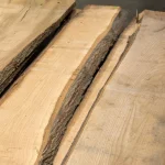 Top view of several unedged red oak boards showcasing their natural bark edges.