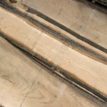 Close-up of multiple unedged red oak boards lying side by side, showing grain variations.