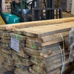 Large bundle of unedged red oak boards with a product label in a warehouse.