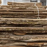 Stacked unedged European walnut boards, 52 mm, with bark edges stored in a warehouse.