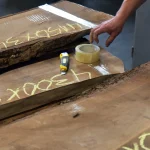 Selecting 52 mm unedged European walnut boards with size markings in a warehouse setting.