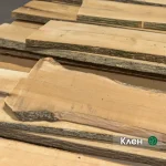 Stack of unedged maple boards of the first grade showing natural bark edges and light wood texture.