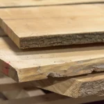 Close-up of the cut ends and rough bark edges of stacked Grade 1 unedged maple boards.