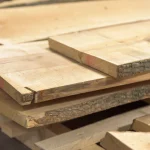 Close-up of the ends of stacked unedged maple boards showing the thickness and natural bark edge.