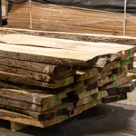 A neat stack of first-grade unedged linden boards on a pallet in a warehouse.