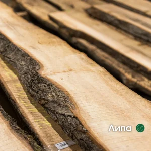 Close-up of an extra grade unedged linden board showing its natural bark edge and light wood texture.