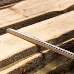 Measuring the width of an unedged linden board using a tape measure.