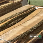 Close-up of unedged alder boards in a stack with chalk markings on the surface.