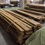 Multiple bundles of unedged alder boards stored in a spacious woodworking warehouse.