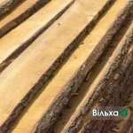 Close-up of unedged alder boards showing natural bark on the edges and warm wood grain.