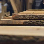 Side view of stacked unedged alder boards showing the thickness and natural bark texture.