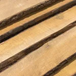 Top-down view of unedged alder boards with beautiful natural wood grain and bark.