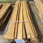 Full stack of 32mm Extra grade unedged alder boards tied with straps in a warehouse.