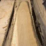Top-down view of a long unedged ash board showcasing its beautiful natural grain pattern.