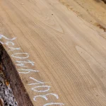 Smooth surface of an extra grade unedged ash board with chalk measurements.