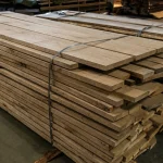 A bound stack of kiln-dried 52 mm edged elm boards in a warehouse storage area