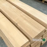 Close-up of premium edged birch lumber boards stacked in a woodworking warehouse.