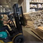 A forklift carries a pallet of edged beech boards, 52 mm, in a warehouse