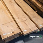 Wide edged cherry lumber boards with marked dimensions and barcode labels on a stack.