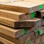 Close-up of the ends of stacked edged cherry boards marked with green paint.