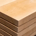 Close-up of stacked edged cherry boards of extra grade, showcasing the smooth wood texture and grain.