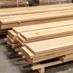 Pallets with neatly stacked long edged cherry lumber boards in a woodworking warehouse.