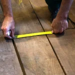 Measuring the width of an American walnut board 55 mm with a yellow tape measure.