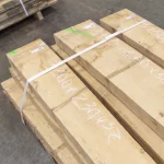 Kiln-dried edged hornbeam boards, 52 mm, bound with strapping tape in a warehouse
