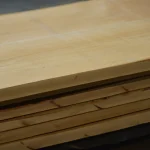 Side view of stacked edged maple boards showing precise thickness and clean cuts.