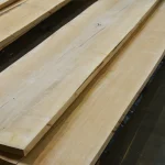 Stacked kiln-dried edged maple boards showcasing clean light-colored wood texture.