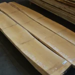 Three long edged maple boards laid out in a warehouse with marked dimensions.