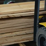 Stack of premium edged maple lumber boards loaded on a forklift in a warehouse.