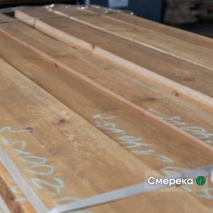 Edged spruce boards of the 1st grade with markings in a tightly packed bundle.